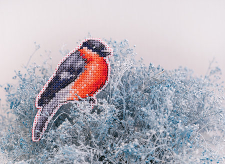 A cross stitched bullfinch on white and blue dried Gypsophila. A bird embroidered by myself. Design by Grigoreva Nadezhdaの写真素材