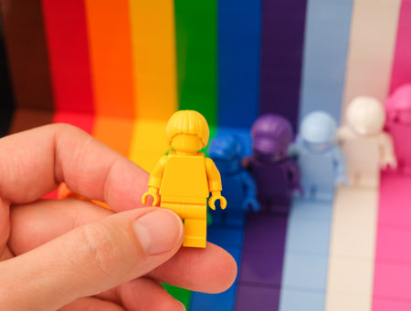 Tambov, Russian Federation - November 09, 2022 A woman hand holding a yellow Lego minifigure above other rainbow minifigures. Lego Everyone is Awesomeのeditorial素材