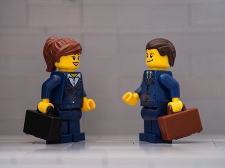Tambov, Russian Federation - March 25, 2023 Lego businessman and businesswoman minifigures meeting on a gray background.のeditorial素材