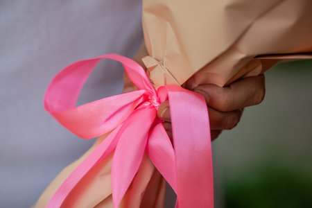 A woman holding a bouquet of flowers with a pink bowtie with one hand. Close-up.の写真素材