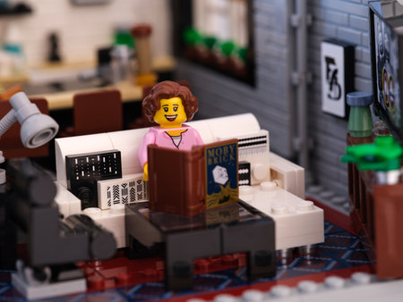 Tambov, Russian Federation - July 02, 2023 A Lego woman minifigure sitting on a couch and reading a bookのeditorial素材
