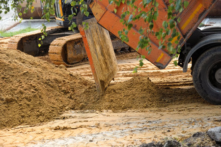 A dump truck dumping sand at a construction site. Close-up