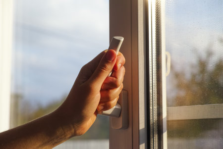 A woman hand opening a window using a window handle.