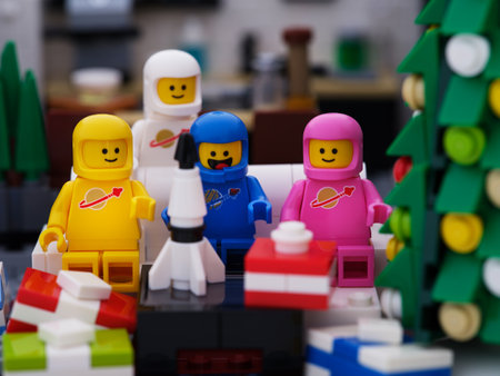Tambov, Russian Federation - September 24, 2023 Four Lego astronaut minifigures - Benny, Lenny, Kenny, Jenny sitting on a couch during Christmas and opening gift with a toy rocket insideのeditorial素材