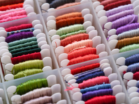 A lot of plastic bobbins with different colour embroidery threads in a plastic sorting box.の写真素材