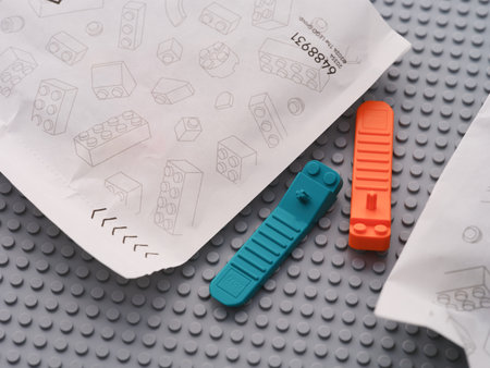 Tambov, Russian Federation - June 22, 2024 Lego brick separators lying between paper bags with Lego pieces on a gray baseplateのeditorial素材