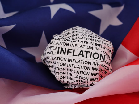 Crumpled paper ball with words Inflation lying on an American flag.の写真素材