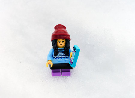 Tambov, Russian Federation - March 10, 2024 Lego girl minifigure holding a smartphone and standing...