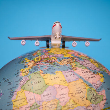 Airplane on a globe against a blue background. Flight around the worldの写真素材