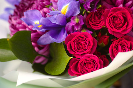 Close-up shot of a bouquet of irises, roses, chrysanthemums and alstroemerias in paper wrappingの写真素材