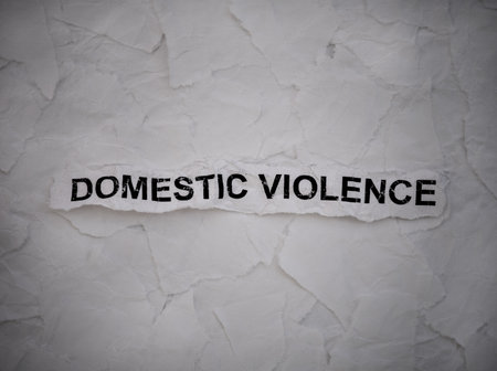 Crumpled piece of a paper with words Domestic Violence on torn white paper pieces background.の写真素材