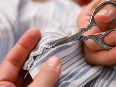 Close-up shot of woman hands with scissors cutting open the basting stitch on the clothes