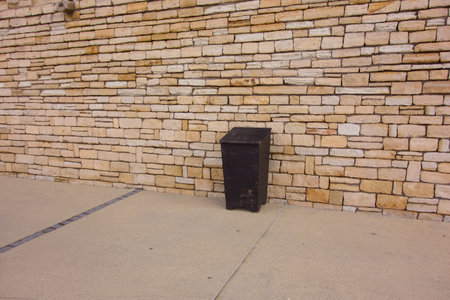 Black wooden garbage can standing against a stone wall outdoorsの写真素材