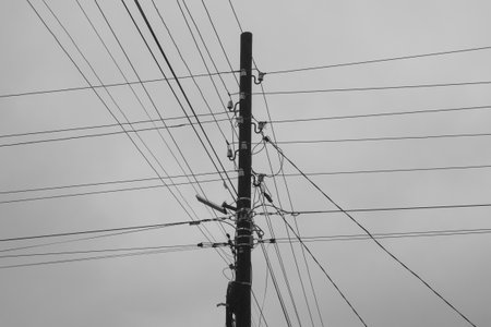An electric post with many power lines on it. Black and white.