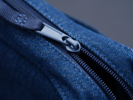 Close-up shot of a zip on a denim bag.