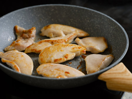 Slices of chicken breast cooking in a frying panの写真素材