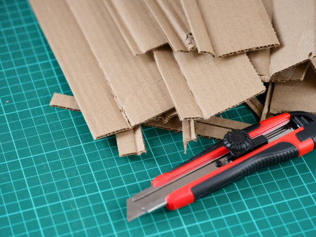Heap of cardboard pieces and paper knife lying on green cutting mat.の写真素材