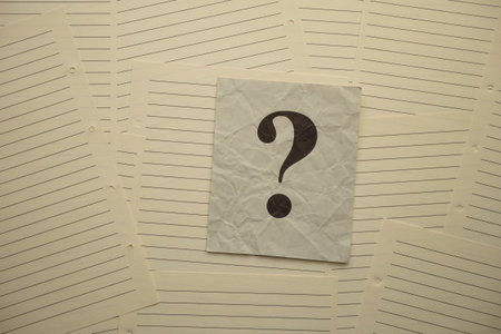 Crumpled gray paper note with question mark on it lying on lined notebook pages.
