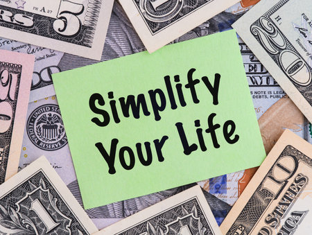 Green paper note with phrase Simplify Your Life on a United States Dollar bills background.