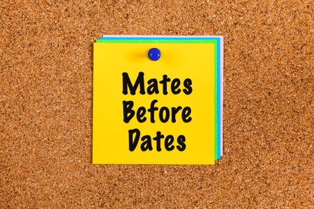Yellow paper notes with words Mates Before Dates on a corkboard