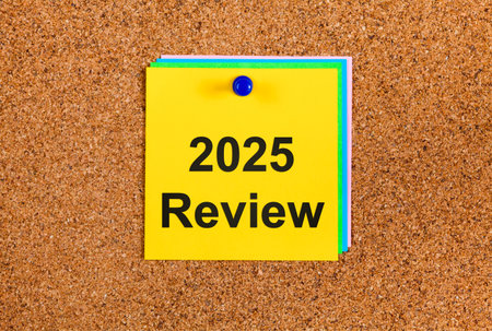 Yellow paper note with words 2025 Review on cork board