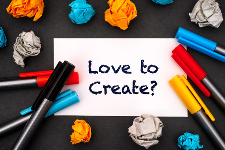 White paper blank with words Love to Create? with colour pens and crumpled paper balls around it on...