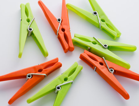 Close-up of green and orange clothespins on a white background.の写真素材