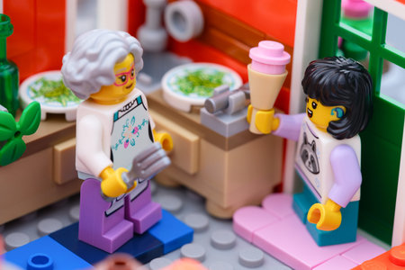 Tambov, Russian Federation - January 27, 2026 Lego girl minifigure bring a pink ice cream cone to her grandmother, who is cooking in the kitchen.のeditorial素材