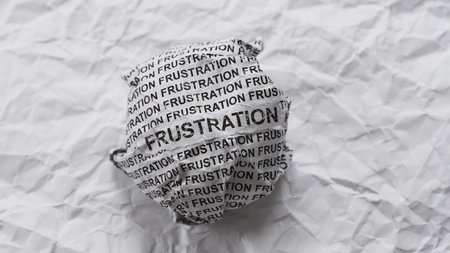 Crumpled paper ball with words Frustration on crumpled white paper background.