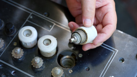 Close-up of a person hand with white ceramic plug fuse screwing from old black electrical panelの写真素材