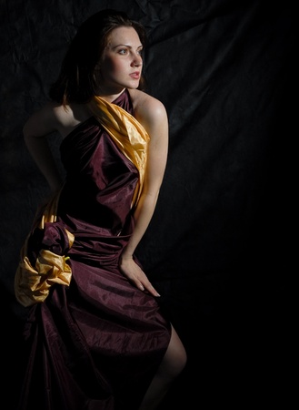 Model posing in satin dress on black backgroundの写真素材