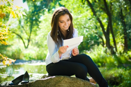 Young beautiful woman reading good news in parkの写真素材