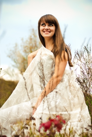 Young beautiful woman sitting among autumn flowersの写真素材