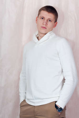 Handsome young man in white sweater studio portraitの写真素材