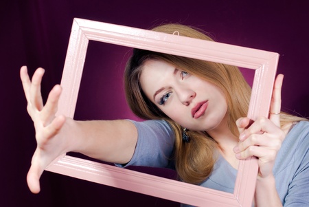 Young woman trying to reach through frameの写真素材