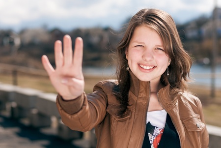 Happy smiling teenage girl showing four fingersの写真素材