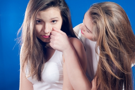 Two young women comforting each other and wiping tears over bluescreenの写真素材