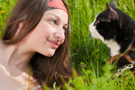 Young beautiful teenage girl with blue eyes portrait on green grass and black catの写真素材
