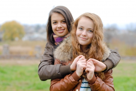 Two young best teenage girlfriends female women hugging eachother outdoors on autumn dayの写真素材