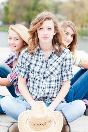 Three happy girls sitting together outdoorsの写真素材