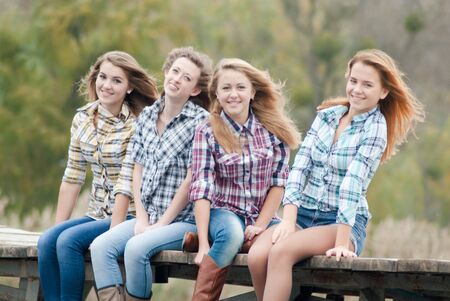 Four girls sitting on river bridge