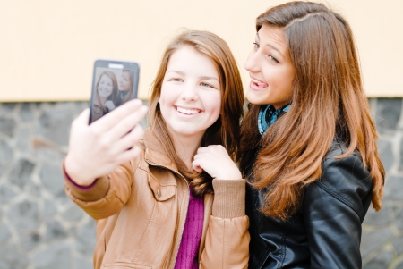 Two teen girls taking picture of themselves using tablet computerの写真素材