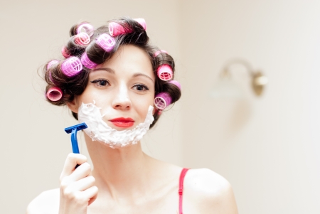 Beautiful funny young woman shaving with foam   razor her faceの写真素材