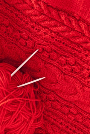 Detail of woven handicraft knit woolen design texture and knitting needle. Fabric red background