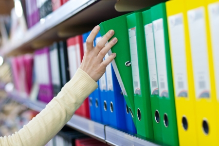 woman's hand holding big folder from the shelves with office files.の写真素材