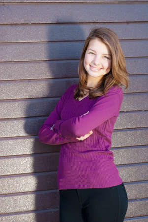 Outdoors portrait of beautiful happy smiling young brunette woman with hands crossed