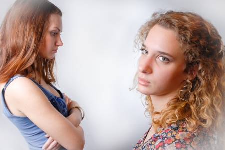 Two beautiful young girls talking privately on white backgroundの写真素材