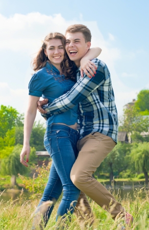 Happy teenage couple boy and girl embracing over blue sky backgroundの写真素材