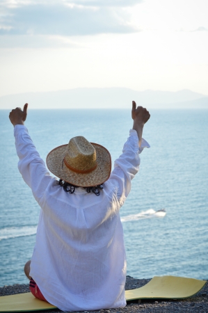 Successful man sitting on coastline showing thumbs upの写真素材