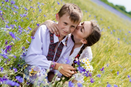 Teenage sister and little brother together on summer wheat fields